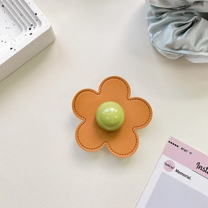 Detail of orange lychee leather flower phone grip with green bead center and fine stitching