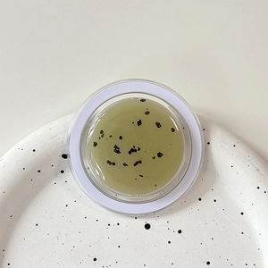 Close-up of translucent yellow facial mask gel with natural botanical particles in a jar