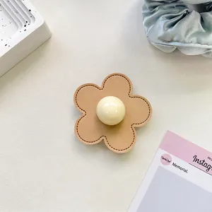 Detail of flower phone grip with beige leather stitching and large center pearl accent
