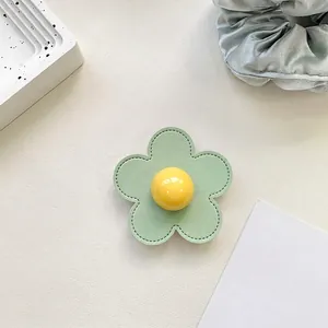 Detailed view of flower phone socket with green leather petals and yellow center bead