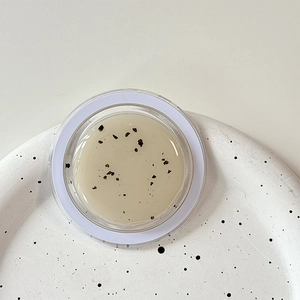 Close-up of translucent facial cream with botanical particles in a glass jar