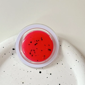 Macro shot of watermelon lip balm with seeds texture on a white ceramic tray