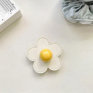 Detailed top view of a white leather flower phone grip with a yellow center button