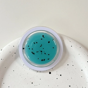 Detail of teal glitter magnetic phone stand with black flecks on a ceramic tray