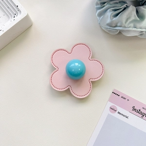 Detail of pink leather flower phone grip with blue glossy center and white stitching