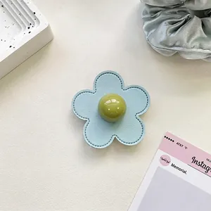 Detail of light blue leather flower phone grip with central green bead and fine stitching