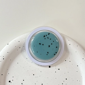Detail of teal Oreo-style MagSafe phone grip with black spots and glossy resin finish
