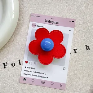 Detailed view of flower phone grip with red stitched petals and blue round center