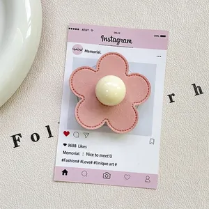 Macro detail of a pink leather flower phone grip with stitching and a central pearl accent