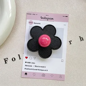 Detail of flower phone grip with black leather texture and pink glossy sphere center