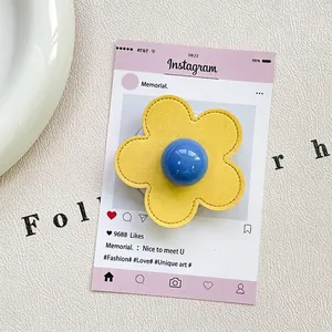 Detailed close-up of yellow leather flower phone grip with blue bead accent on a card