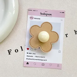 Detailed view of camel leather flower phone grip with stitching and creamy bead center