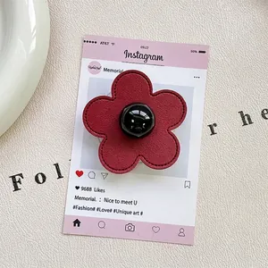 Close-up of wine red leather flower phone grip with stitching and black sphere center