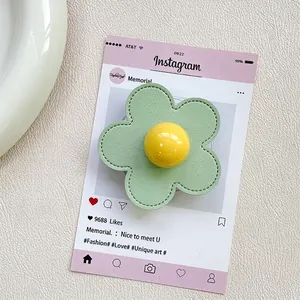 Detailed view of handmade light green leather flower phone grip with stitching details