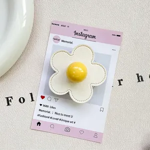 Detail of flower phone grip featuring white faux leather petals and yellow center