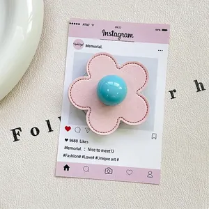 Detailed view of pink leather flower phone grip with blue bead center on white texture