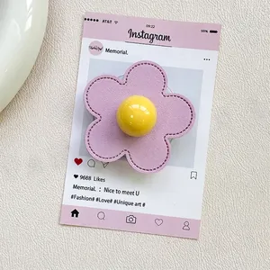 Macro detail of purple flower phone grip with stitching and a yellow center bead