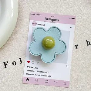 Macro detail of a light blue leather flower phone grip with a green resin bead center