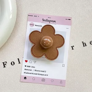 Detail of flower phone grip made of brown leather with fine stitching and bead center