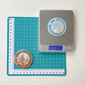 Macro view of starfish phone grip showing 23.2g weight on digital scale and clear base