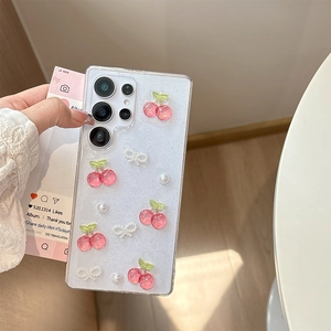 Detail view of transparent glitter phone case with 3D cherry and pearl bow decorations