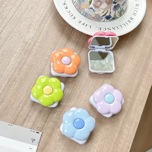 Set of five colorful flower-shaped folding mirrors on light wood background