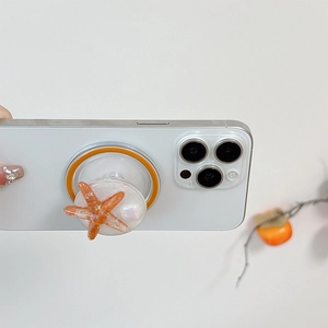 Close-up of sparkling orange starfish phone grip with glitter on a white smartphone