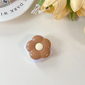 Close-up of a floral phone grip with brown petals, white center, and expandable base
