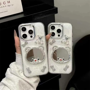 Sparkly white iPhone case with mirror bear and rhinestone bow details shown in hand
