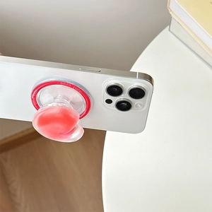 Detail of pink heart-shaped phone grip with 'GOOD LUCK' text on a white smartphone