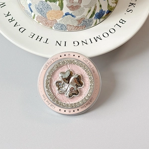 Macro shot of pink foldable phone grip with silver clover and sparkling rhinestones