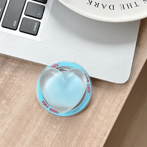 Detail shot of light blue matte heart phone grip with Good Luck text on wood surface