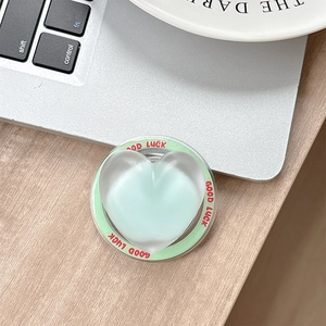 Macro detail of mint green heart phone socket with Good Luck text on a wooden desk