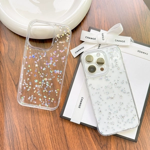 Dettaglio della cover iPhone trasparente con stelle olografiche su tavolo in legno con regalo