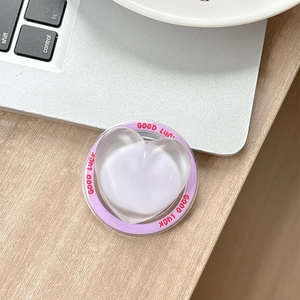 Macro view of heart-shaped phone grip with Good Luck text on a purple base