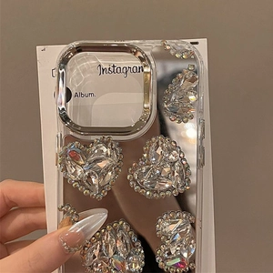 Detailed view of iPhone case featuring large 3D heart rhinestones and silver camera frame