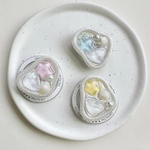 Supporti per telefono con perle e stelle colorate su un vassoio di ceramica bianca