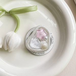 Dettaglio del supporto per telefono con stelle rosa, perle e conchiglie marine