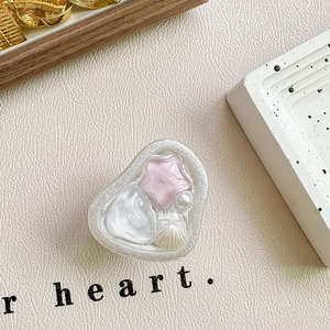 Vista macro di un supporto per telefono a cuore con stelle rosa, perle e conchiglie