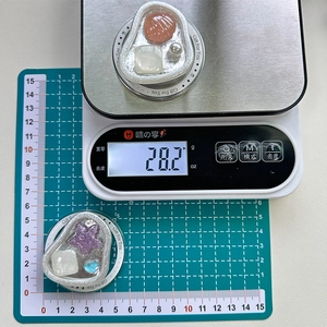 Detail view of pearl shell phone grip on scale showing 28.2g weight and 5cm size