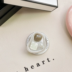Detail of vintage resin phone grip with shell, pearl and square gem on beige leather surface