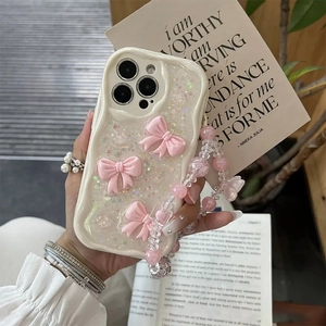 Close-up of glitter iPhone case with 3D pink bows and beaded charm strap on hand