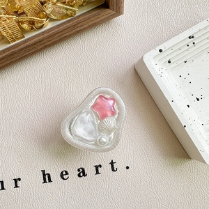 Dettaglio del supporto per telefono a cuore in resina con perle, conchiglie e glitter