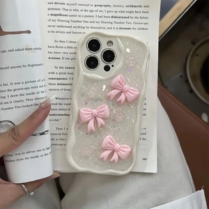 Glittery iPhone case with pink 3D bows and wave edges on an open vintage book