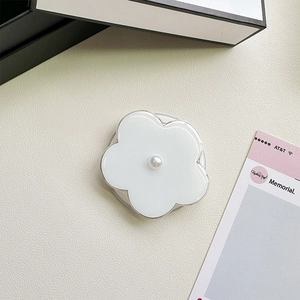 Detailed view of white resin flower phone grip with pearl accent on leather surface