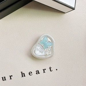 Macro shot of heart-shaped phone grip with blue butterfly and pearl accents on leather