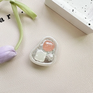 Detail view of pink shell heart and pearl decor on a folding phone airbag stand