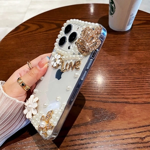 Detail of luxury transparent case with white flowers, pearls, and golden Love lettering
