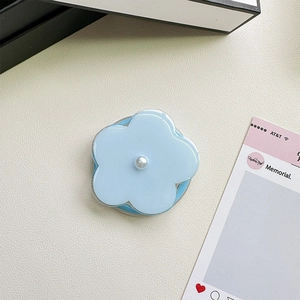 Detail of light blue floral phone grip with a central white pearl on a leather surface