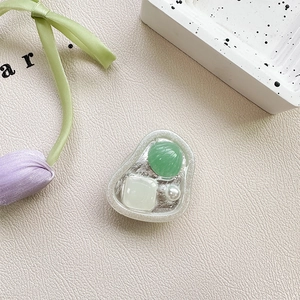 Detail of shell phone grip featuring green stone and white pearl on leather surface